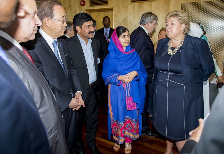 Group of people with girl in blue scarf in centre